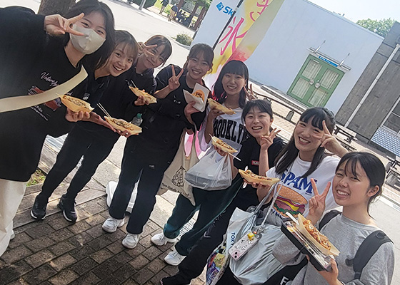 グループがたこやきをもちながらピースをしている写真